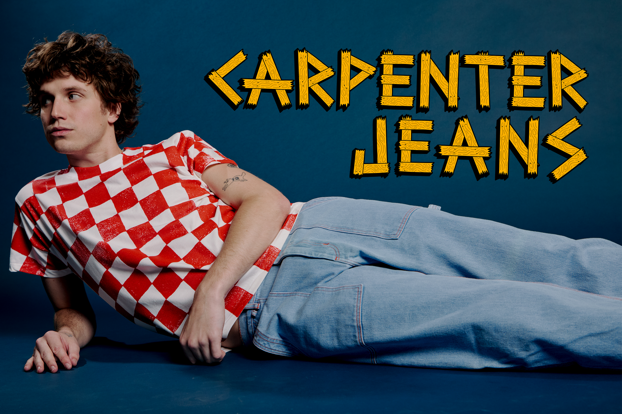 Quinn is wearing light wash Carpenter Jeans paired with the Checker Organic Tee in Red