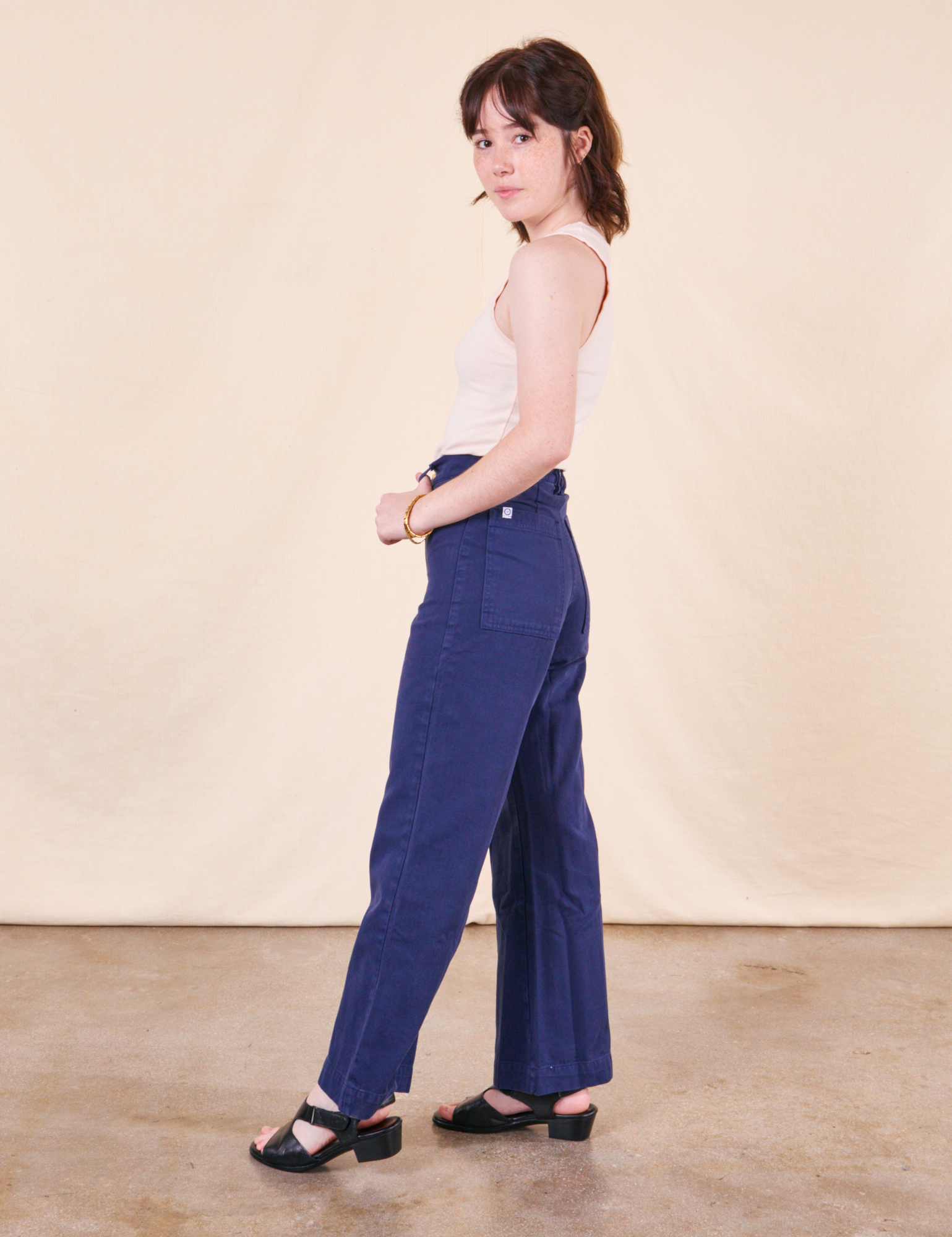 Side view of Western Pants in Navy paired with a vintage off-white Tank Top worn by Hana