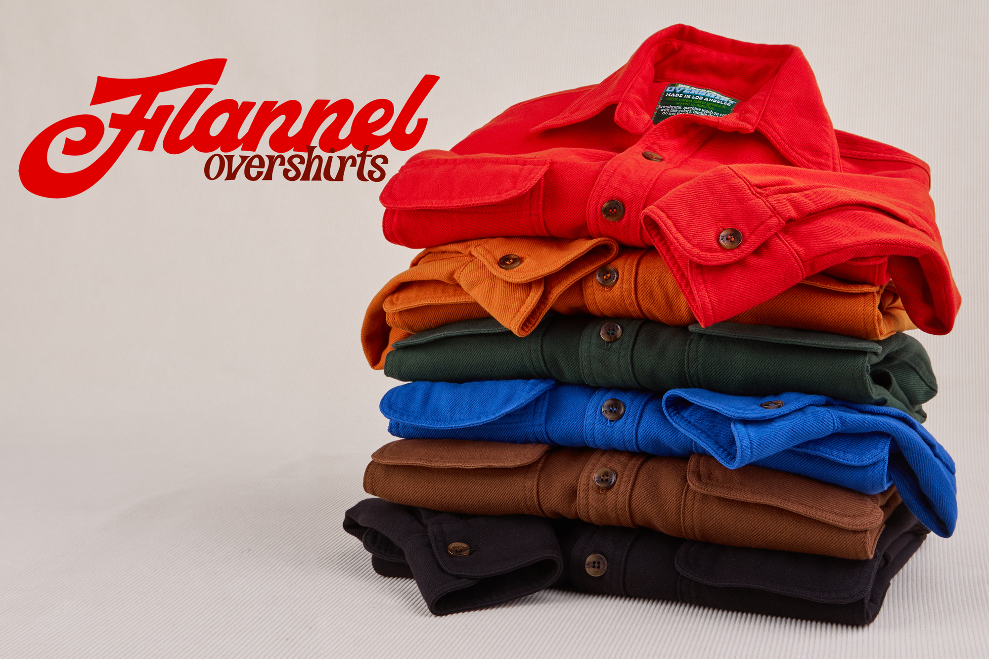 Stack of Flannel Overshirts in mustang red, burnt orange, swamp green, royal blue, fudgesicle brown and black.