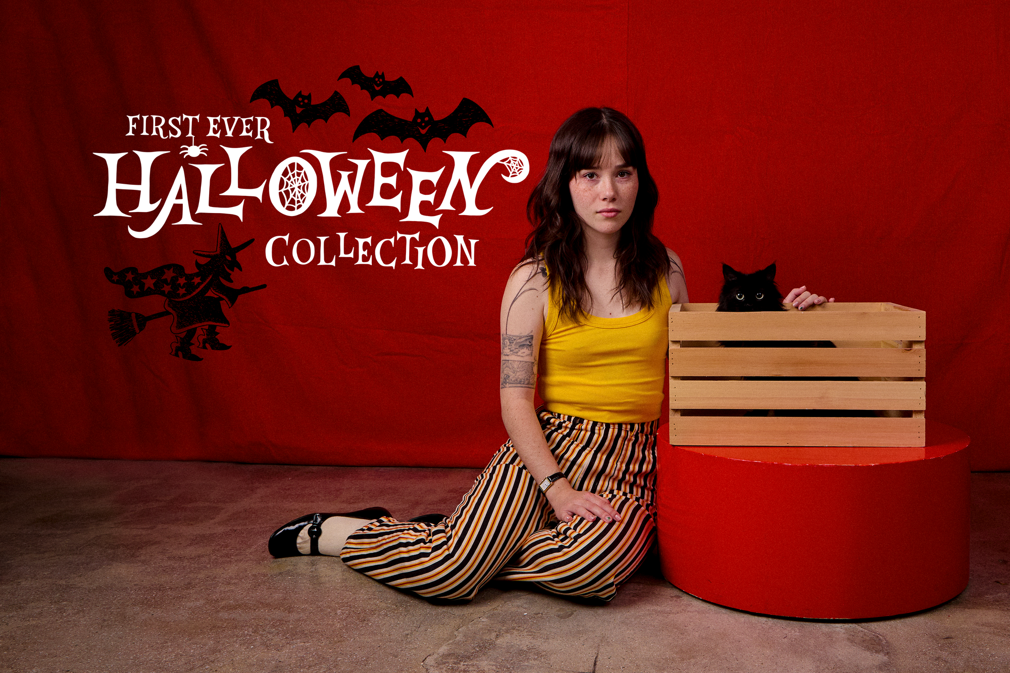 Hana is wearing Stripe Work Pants in Autumn paired with a golden yellow Cropped Tank. Black Cat is in a wooden basket.