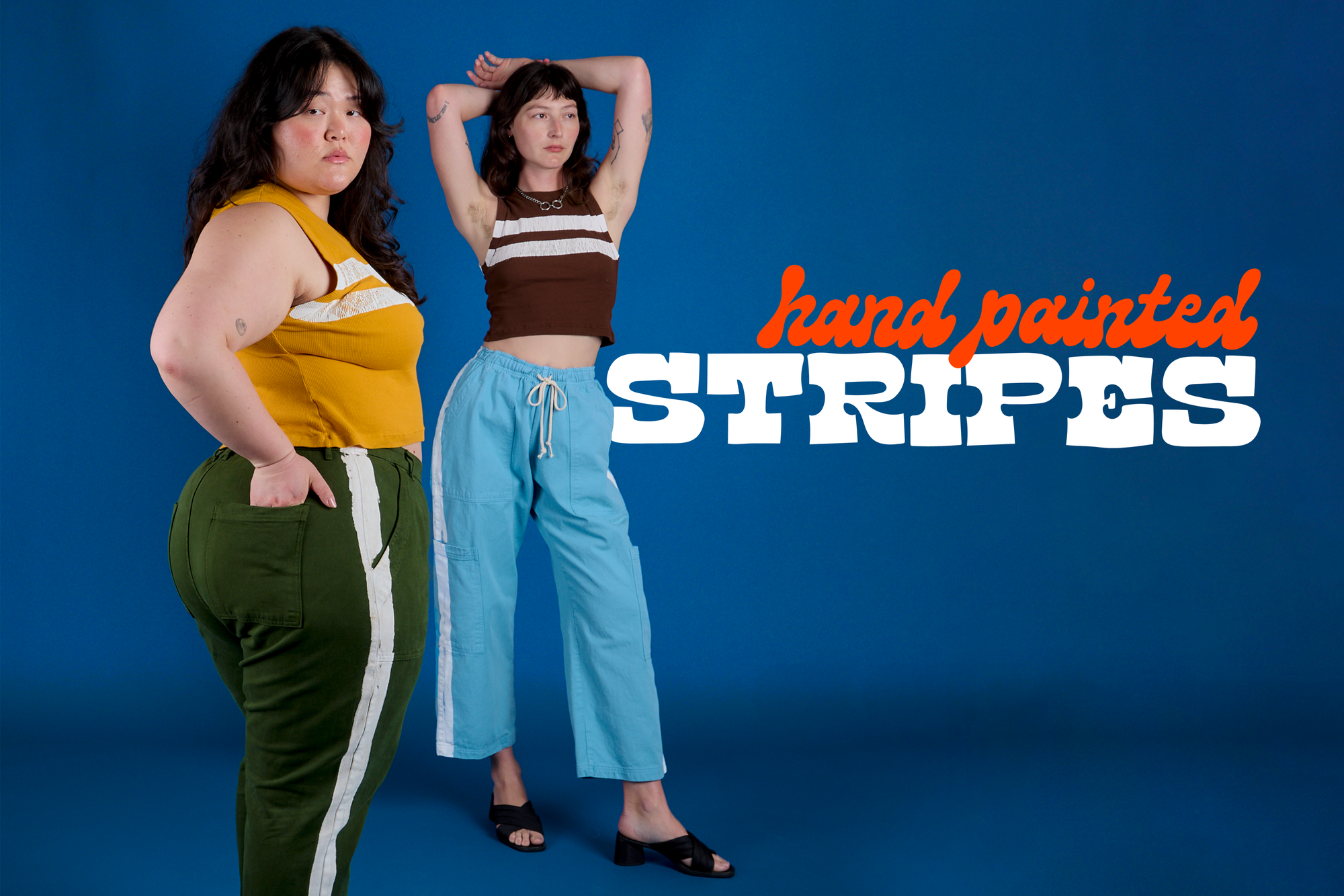 Ashley is wearing Painted Muscle Tee in Mustard Yellow paired with Painted Work pants in Evergreen. Alex is wearing Painted Muscle Tee in Fudgesicle Brown and Painted Drop Pocket Cargo Pants in Baby Blue