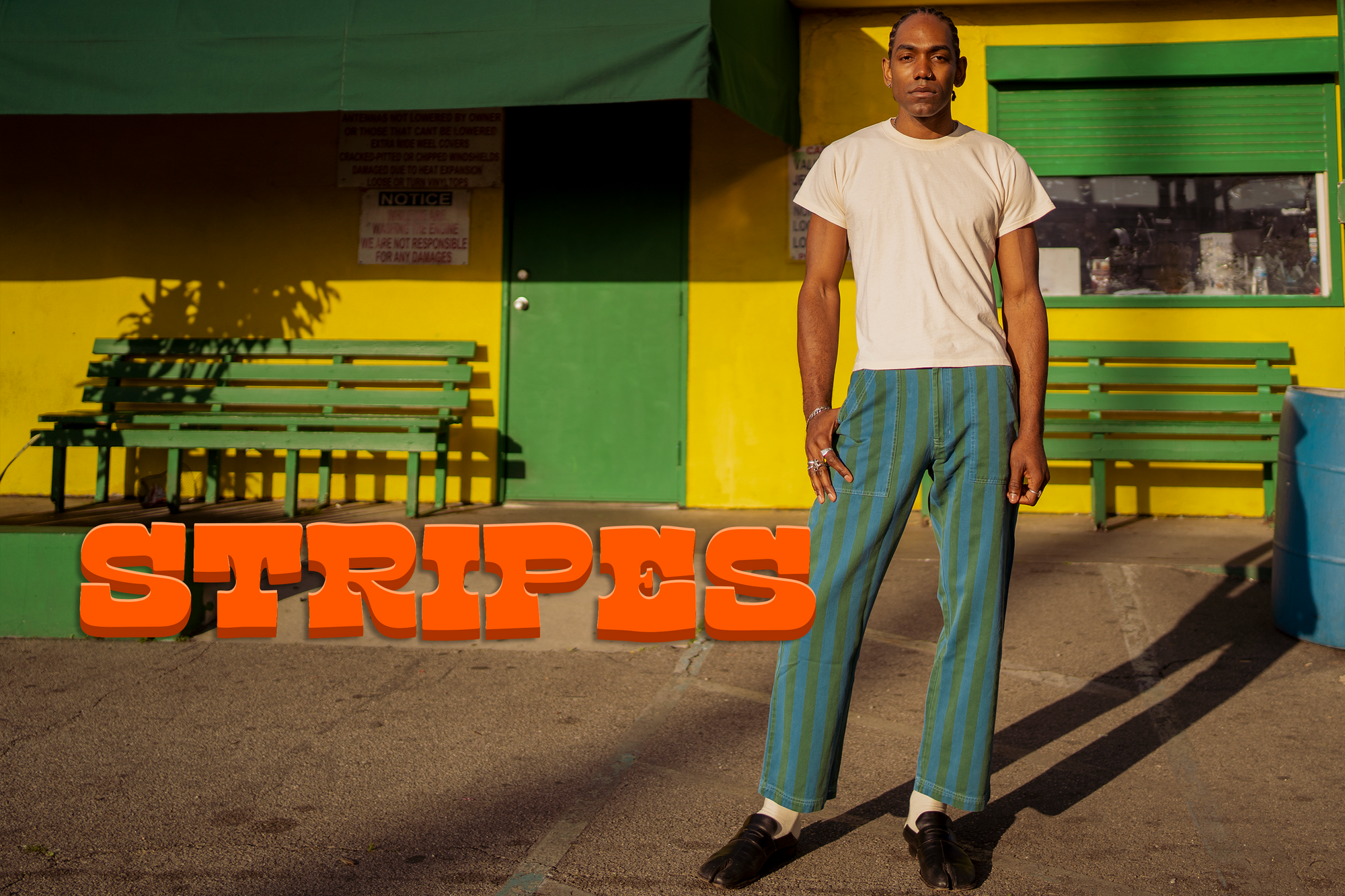 Jerrod is wearing Overdye Stripe Work Pants in Blue and Green paired with a vintage off-white Organic Tee