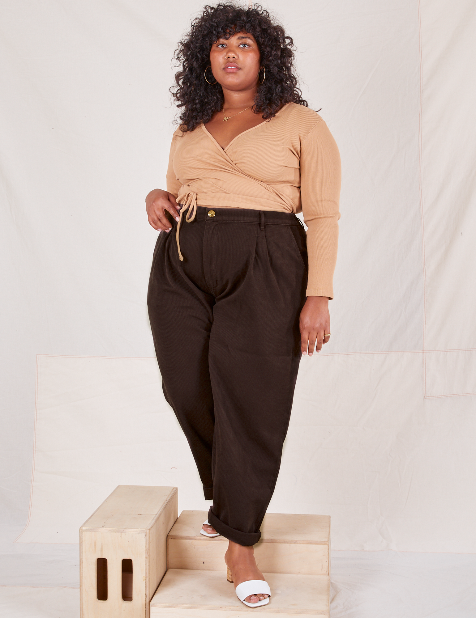 Morgan is 5'5" and wearing 1XL Heritage Trousers in Espresso Brown paired with tan Wrap Top