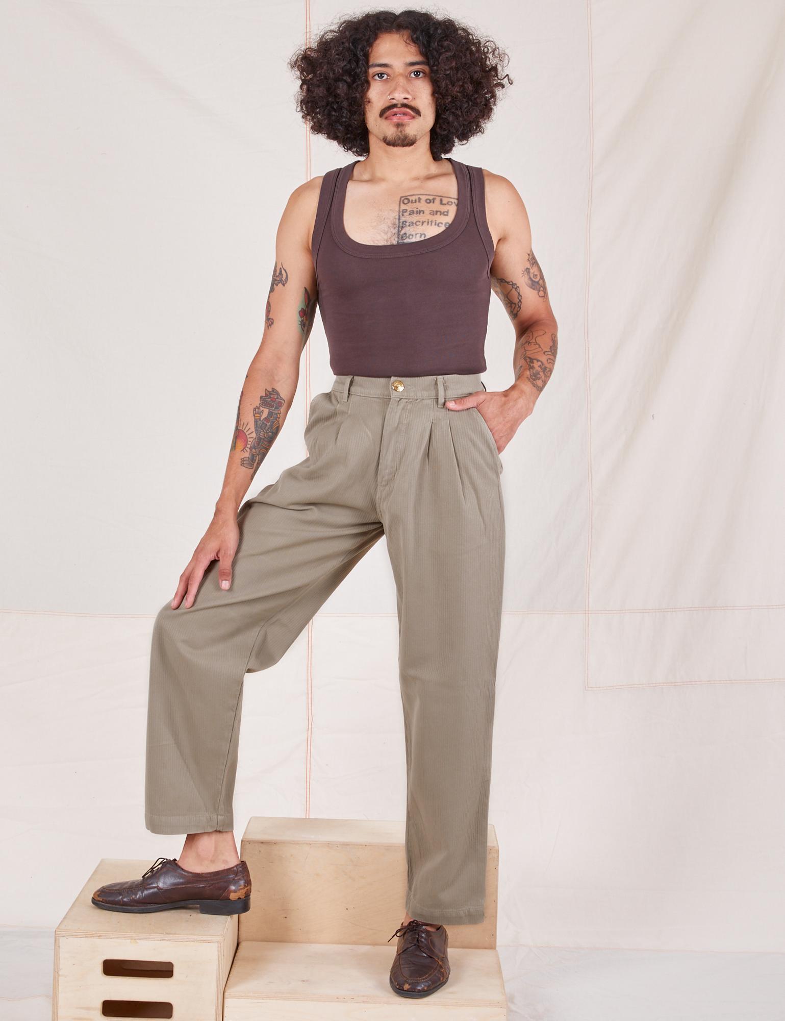 Jesse is 5&#39;8&quot; and wearing XS Heritage Trousers in Khaki Grey paired with espresso brown Tank Top