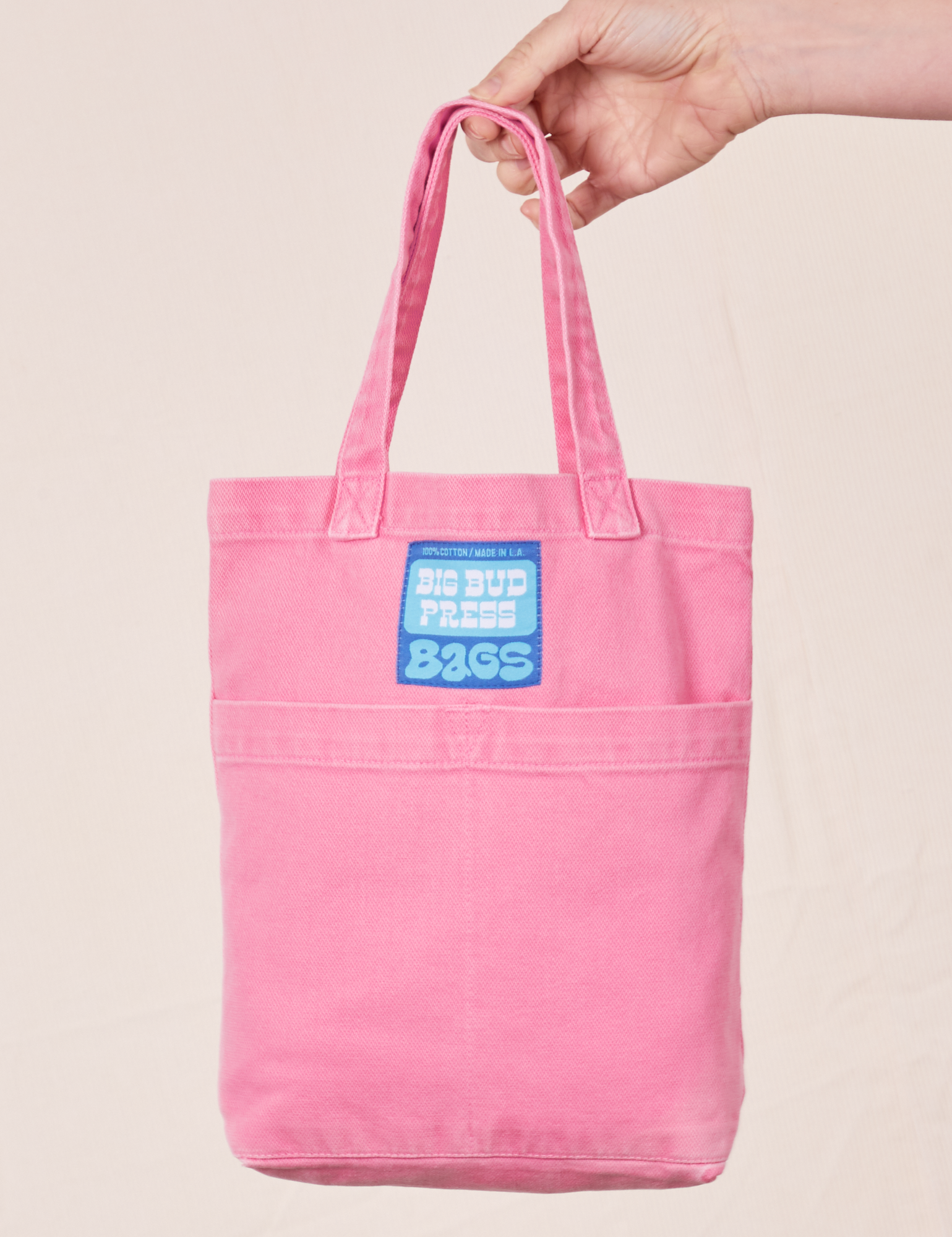 Mini Tote Bag in Bubblegum Pink held by model. Blue Big Bud Press label.