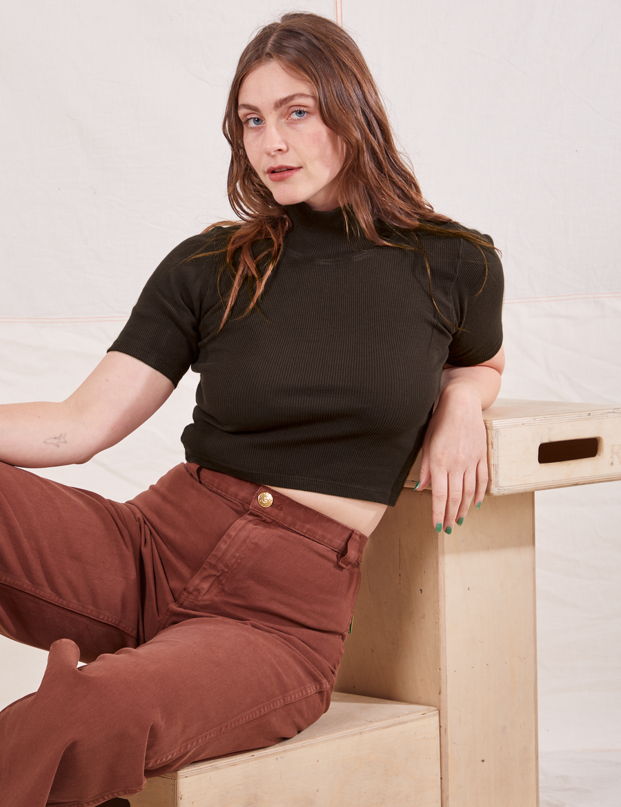Allison is sitting on a wooden crate wearing size XXS 1/2 Sleeve Essential Turtleneck in Espresso Brown paired with fudgesicle brown Bell Bottoms