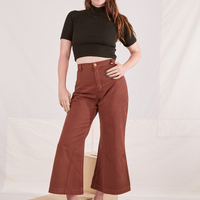 Allison is standing on a wooden crate wearing 1/2 Sleeve Essential Turtleneck in Espresso Brown and fudgesicle brown Bell Bottoms
