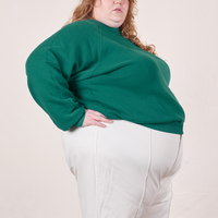 Side view of Heavyweight Crew in Hunter Green and vintage off-white Western Pants worn by Catie