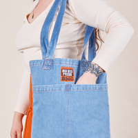 Denim Everyday Tote Bag in Light wash worn by Sydney with hand in front pocket
