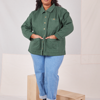Morgan is wearing a buttoned up Denim Work Jacket in Dar Green Emerald. She has both hands in the front pockets.