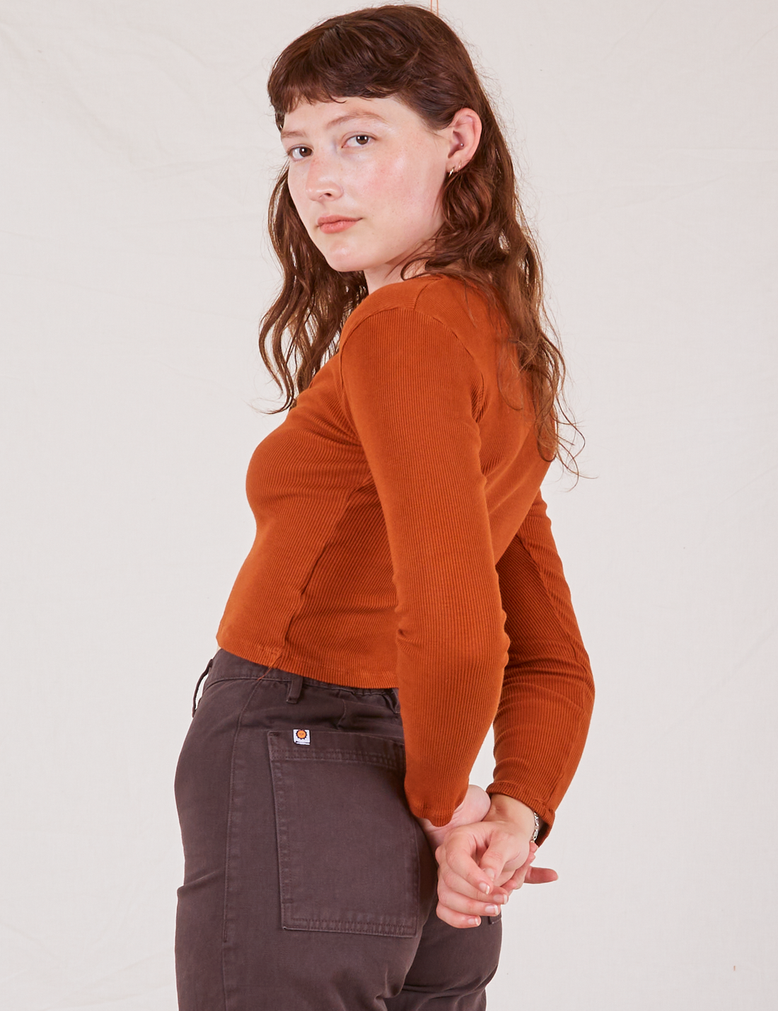 Side view of Long Sleeve V-Neck Tee in Burnt Terracotta worn by Alex