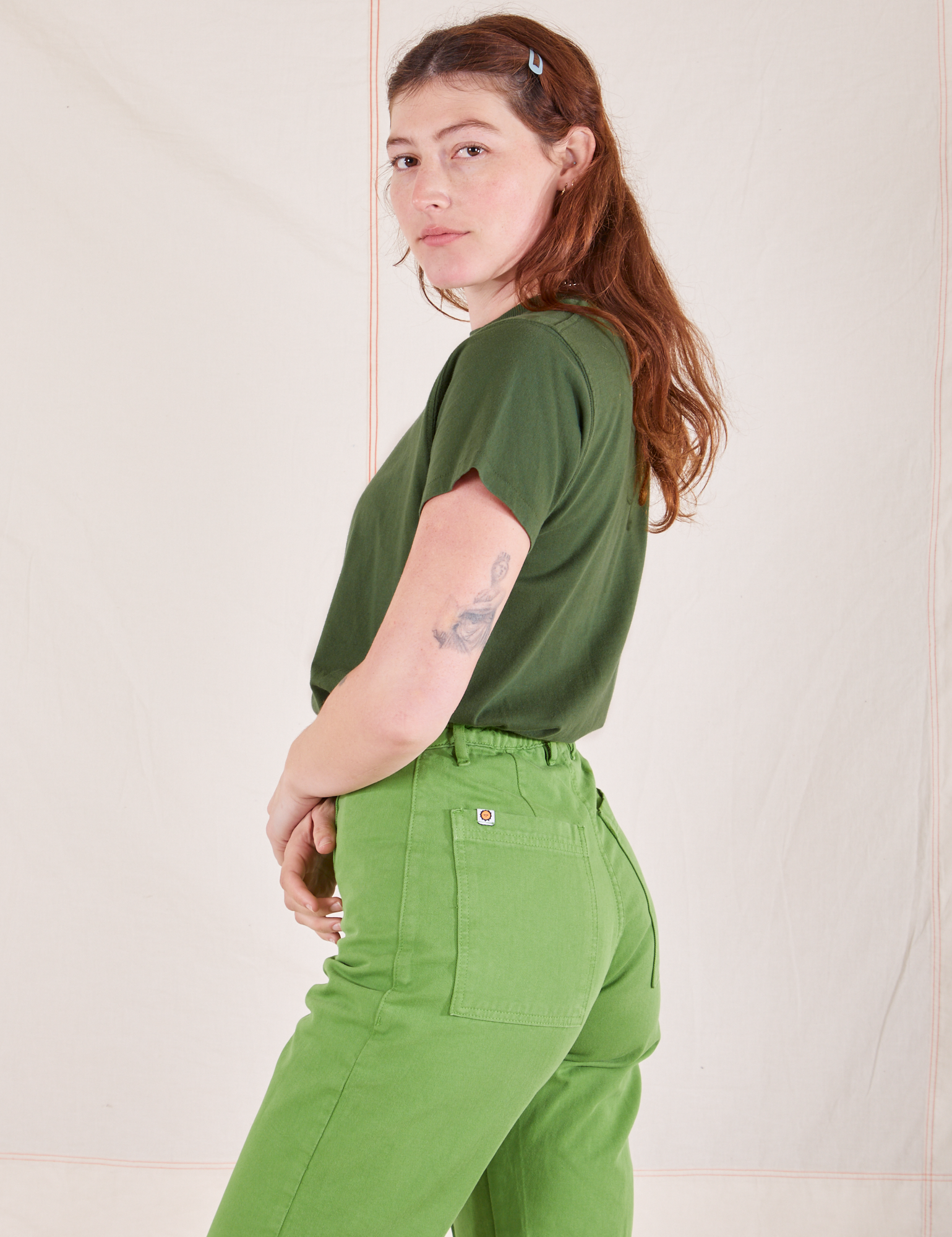 Side view of Organic Vintage Tee in Dark Emerald Green and gross green Western Pants worn by Alex