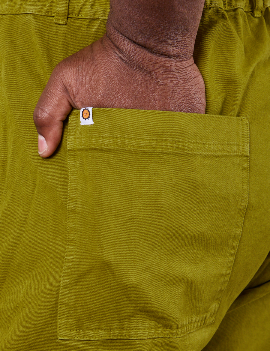 Back pocket close up of Short Sleeve Jumpsuit in Olive Green. Elijah has his hand in the pocket.