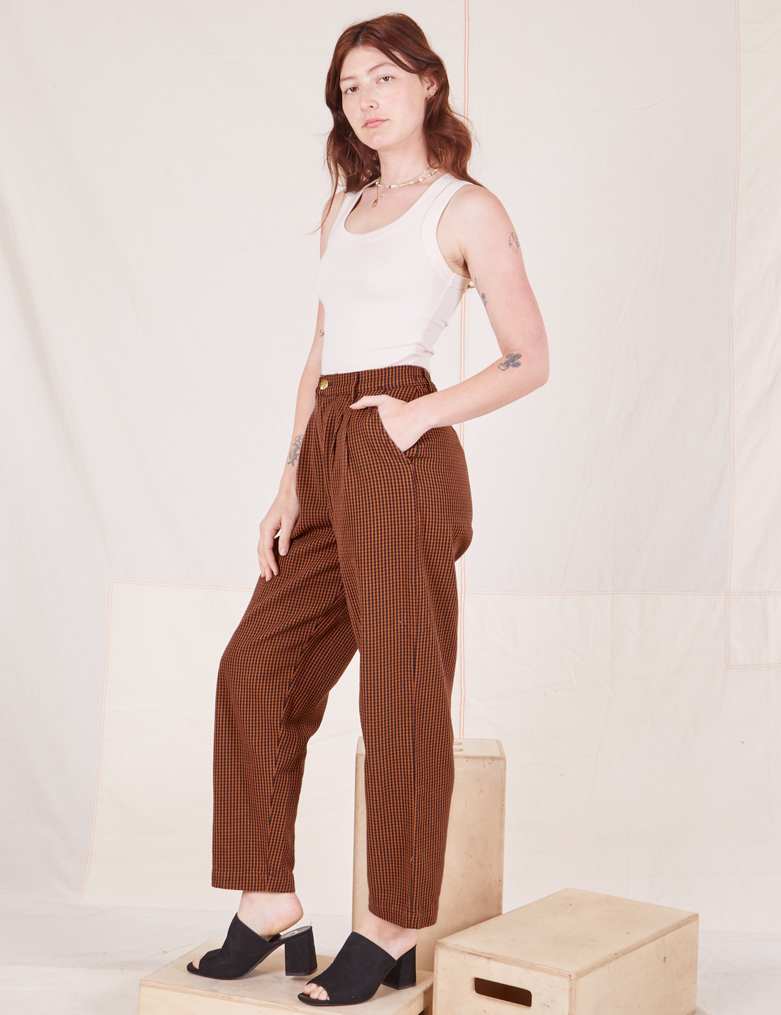 Angled view of Checker Trousers in Brown and vintage off-white Tank Top worn by Alex
