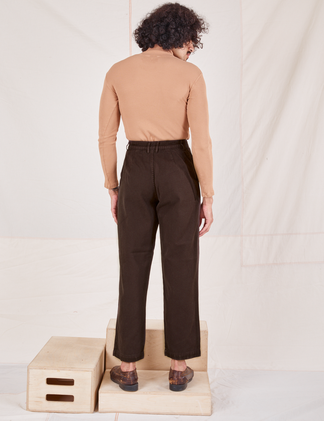 Back view of Heritage Trousers in Espresso Brown and tan Essential Turtleneck worn by Jesse