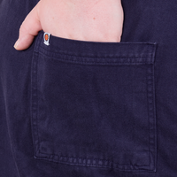 Back pocket close up of Everyday Jumpsuit in Navy Blue. Catie has her hand in the pocket.
