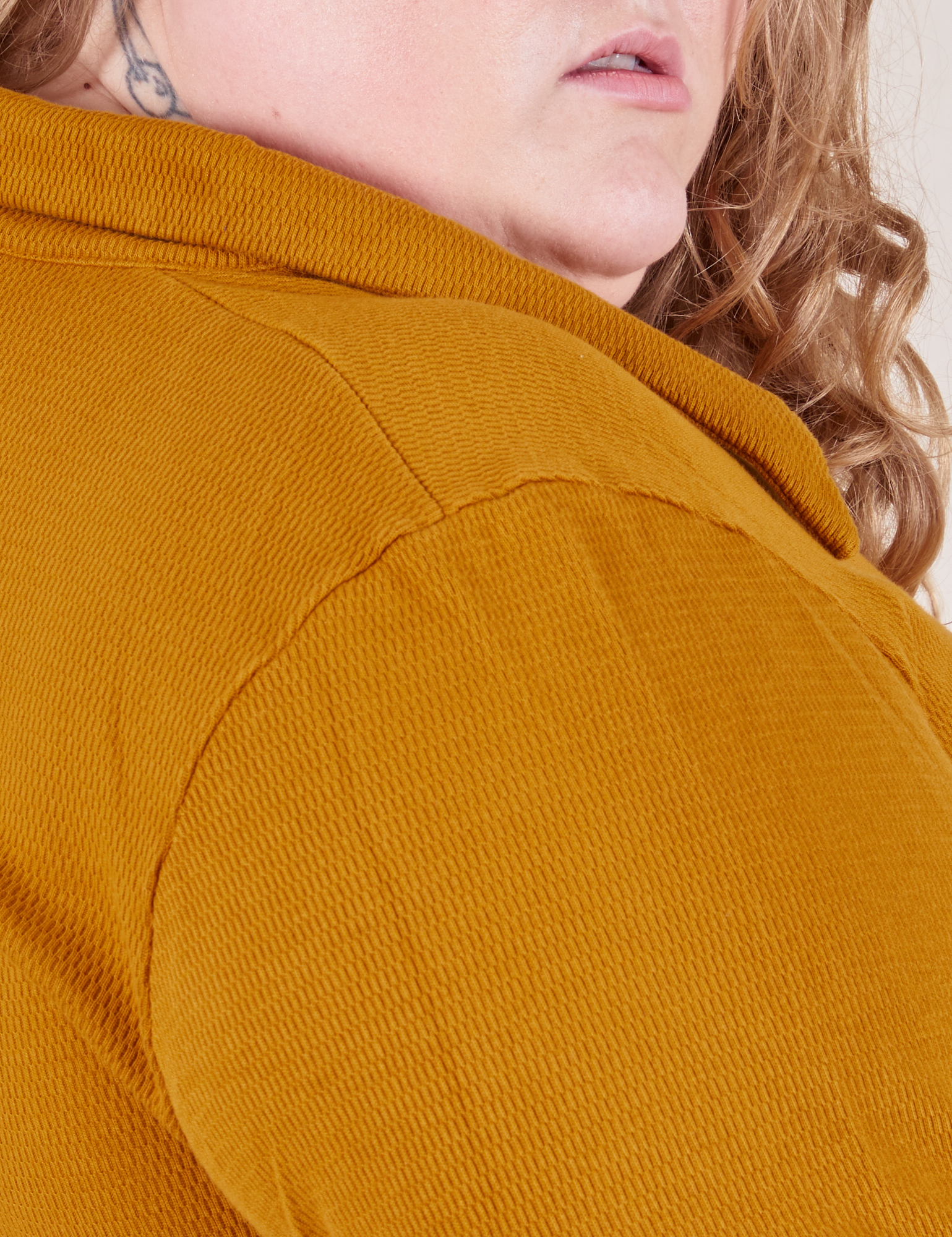 Shoulder close up of Long Sleeve Fisherman Polo in Spicy Mustard worn by Catie