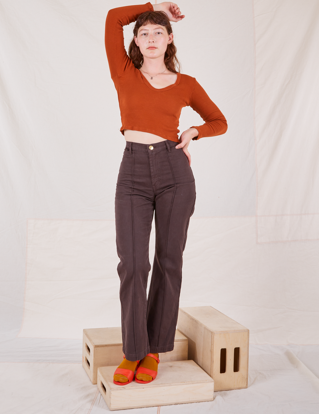 Alex is wearing Long Sleeve V-Neck Tee in Burnt Terracotta and espresso brown Western Pants