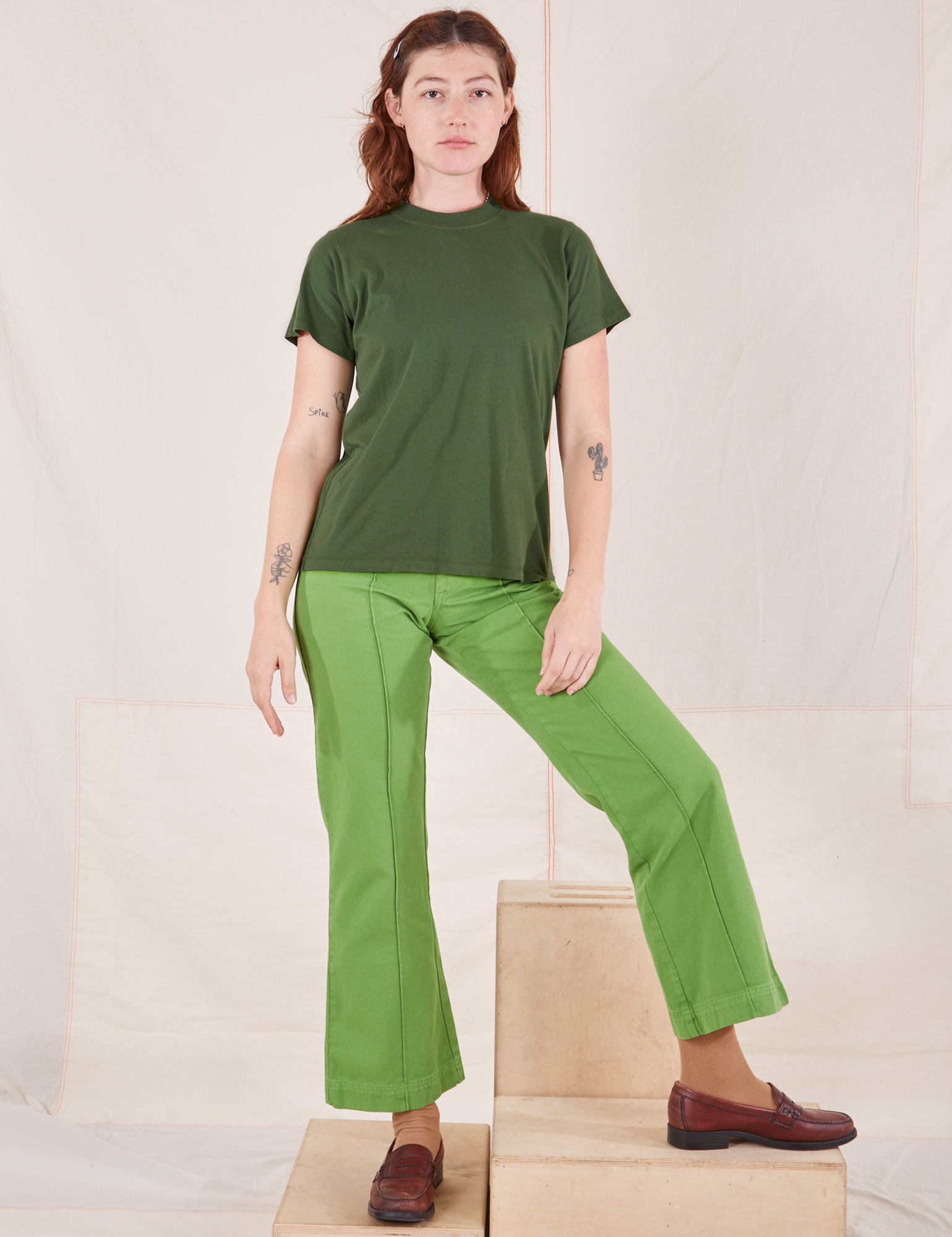 Alex is wearing Organic Vintage Tee in Dark Emerald Green and gross green Western Pants