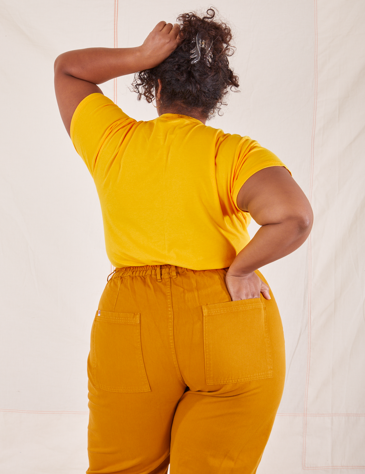 Back view of Organic Vintage Tee in Sunshine Yellow and spicy mustard Western Pants worn by Morgan