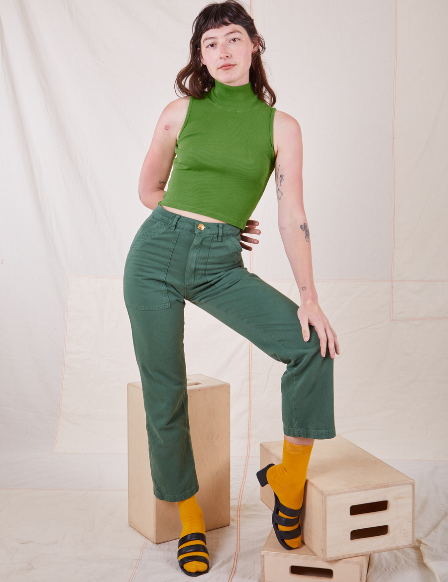Alex is wearing Sleeveless Essential Turtleneck in Bright Olive and dark emerald green Work Pants