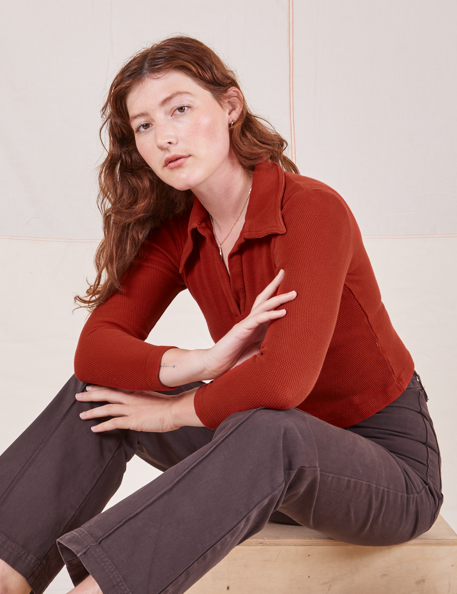 Alex is wearing Long Sleeve Fisherman Polo in Paprika and espresso brown Western Pants