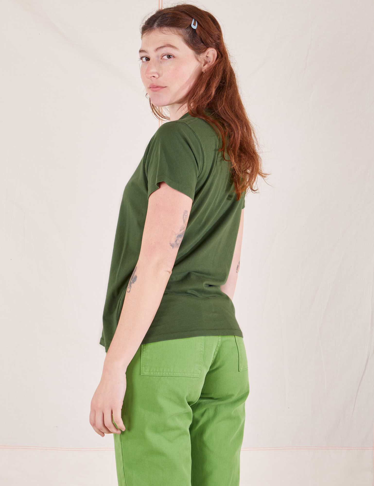 Angled back view of Organic Vintage Tee in Dark Emerald Green and gross green Western Pants worn by Alex