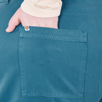 Back pocket close up of Organic Work Pants in Marine Blue. Catie has her hand in the pocket.