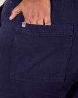 Back pocket close up of Short Sleeve Jumpsuit in Navy Blue. Morgan has her hand in the pocket.