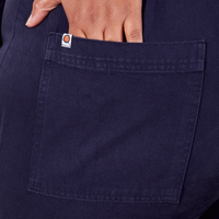 Back pocket close up of Short Sleeve Jumpsuit in Navy Blue. Morgan has her hand in the pocket.