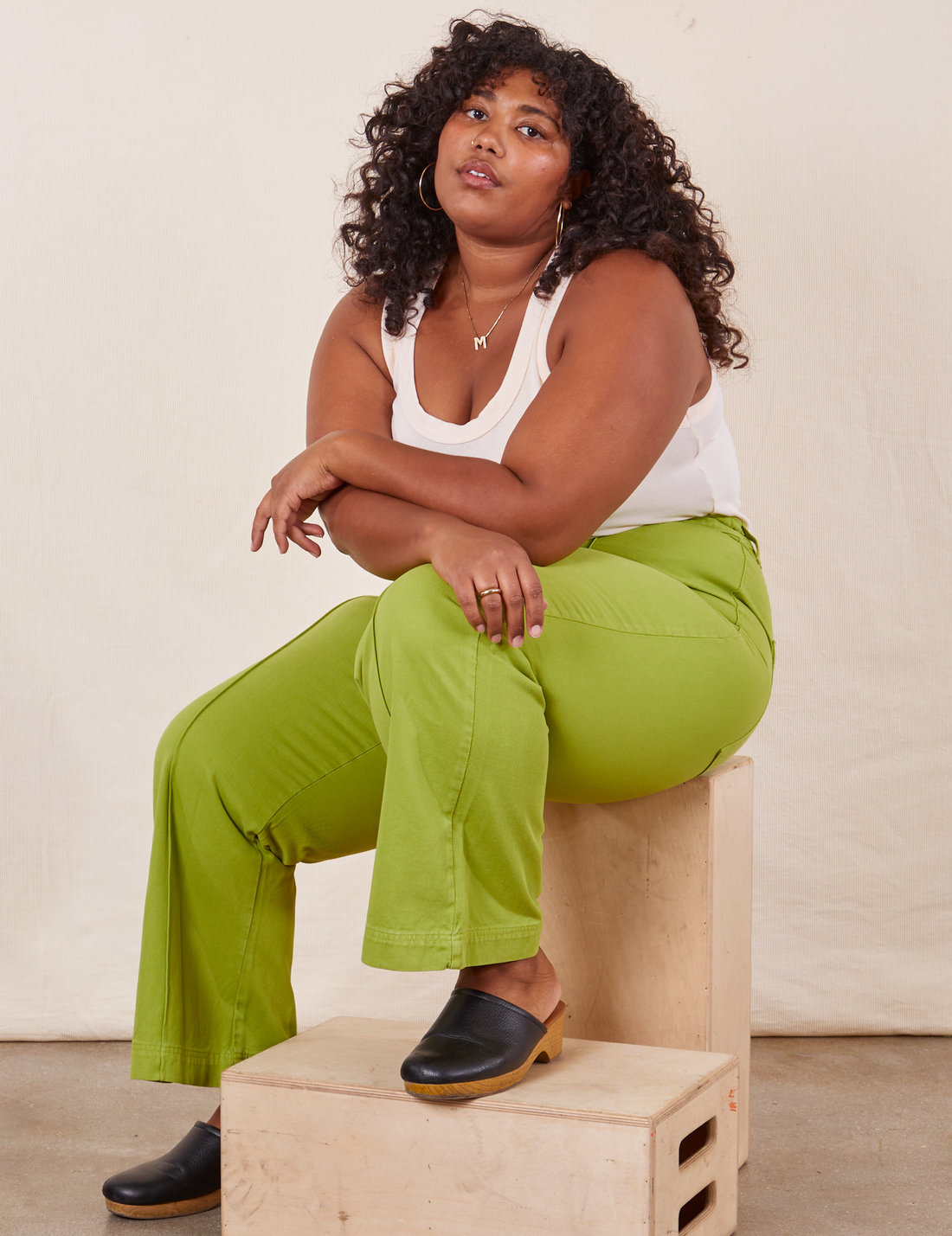 Western Pants in Gross Green on Morgan sitting on wooden crates