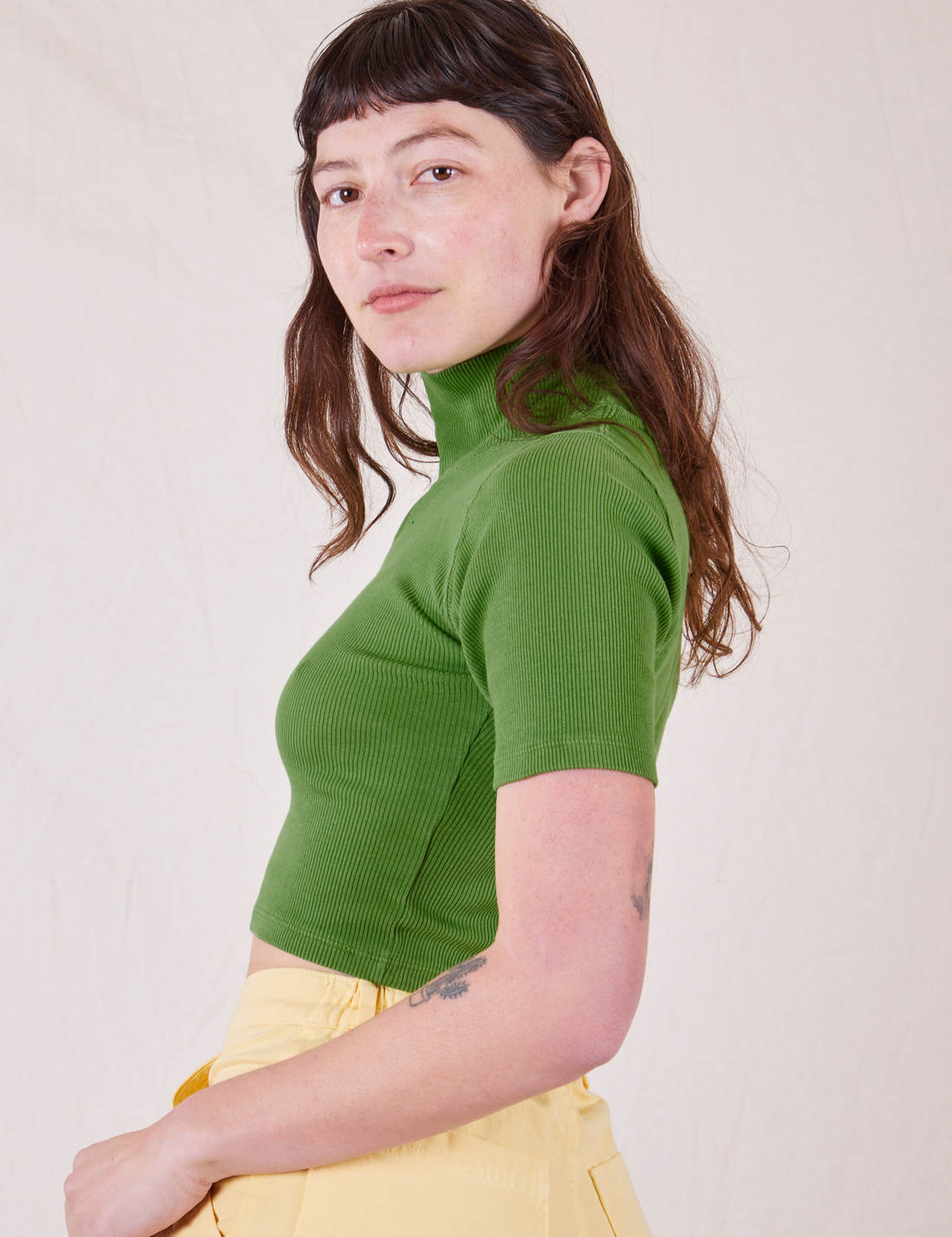 Side view of 1/2 Sleeve Essential Turtleneck in Bright Olive worn by Alex