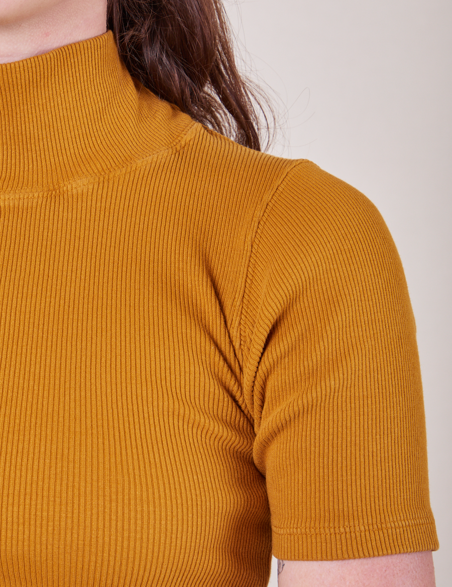 Front shoulder close up of 1/2 Sleeve Essential Turtleneck in Spicy Mustard on Alex