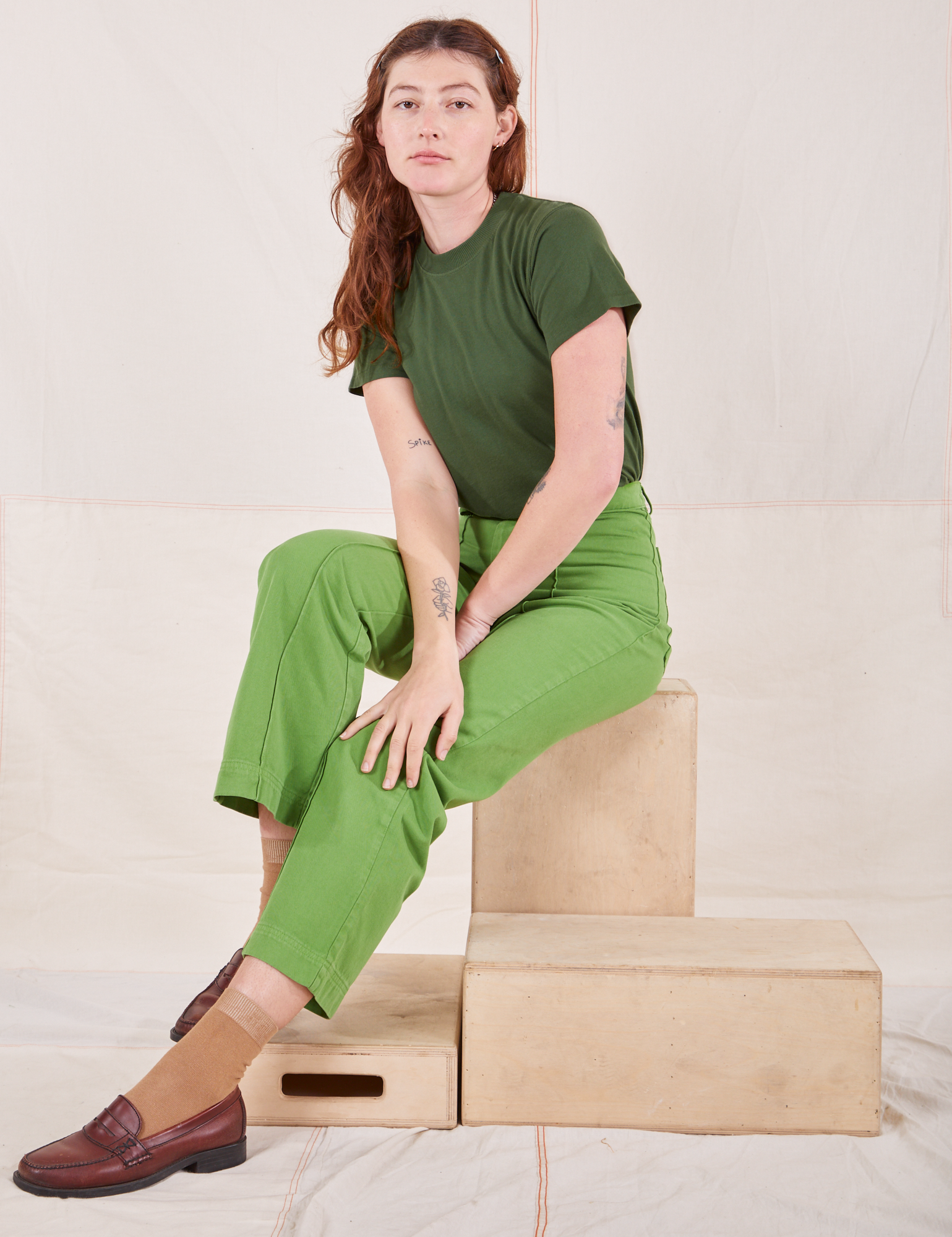 Alex is wearing Organic Vintage Tee in Dark Emerald Green and gross green Western Pants