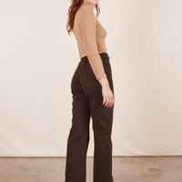 Side view of Western Pants in Espresso Brown paired with tan Essential Turtleneck worn by Alex.
