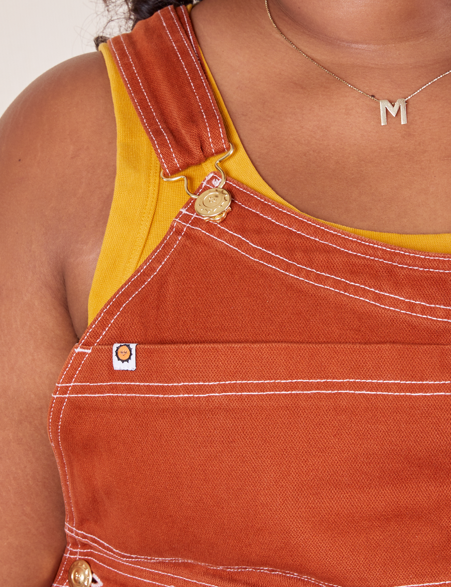 Original Overalls in Burnt Terracotta front close up white stitching and gold hardware