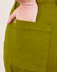 Work Pants in Olive Green back pocket close up. Faye has her hand in the pocket.