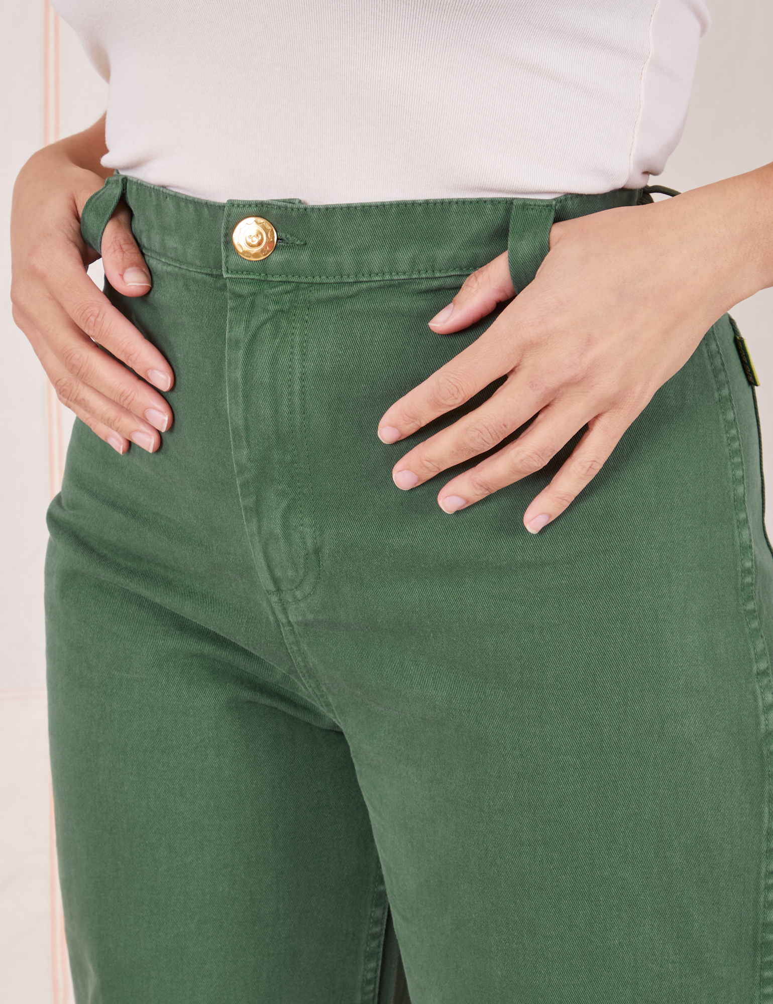 Front close up of Bell Bottoms in Dark Emerald Green. Tiara has her thumbs in the belt loop.