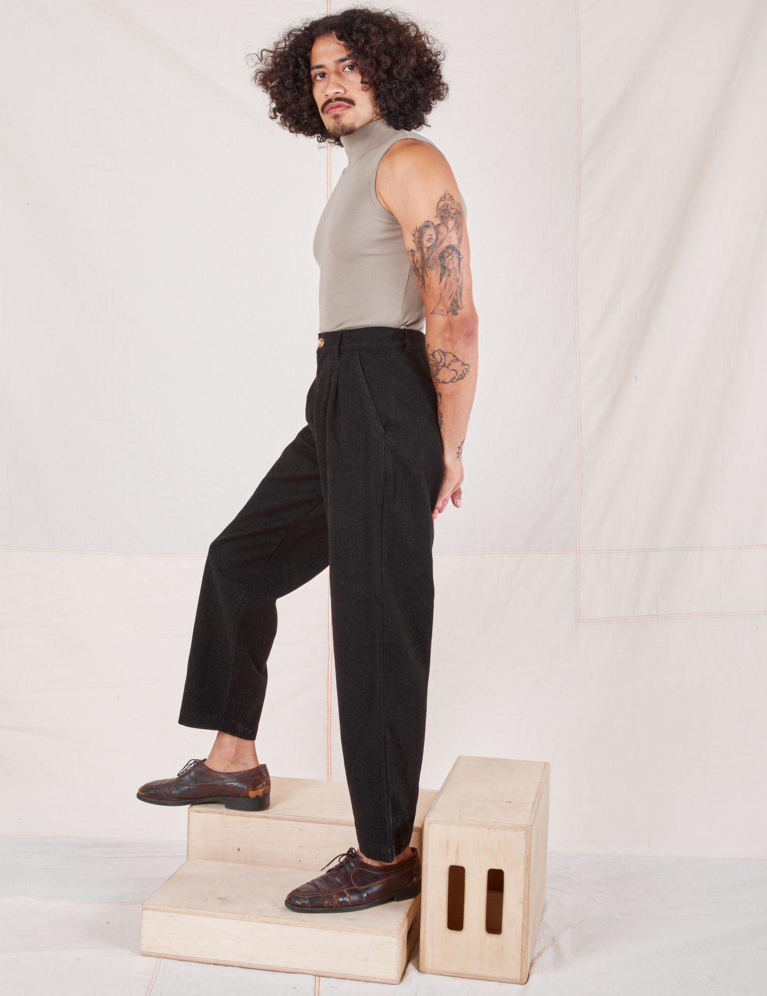 Side view of Heritage Trousers in Basic Black and khaki grey Sleeveless Turtleneck worn by Jesse
