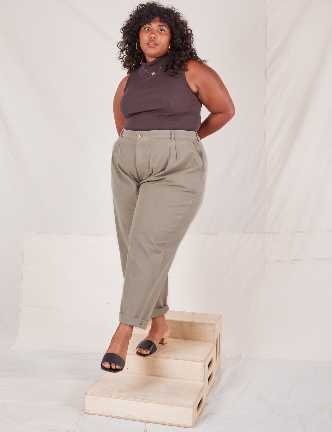 Morgan is 5'5" and wearing 1XL Heritage Trousers in Khaki Grey paired with espresso brown Sleeveless Turtleneck