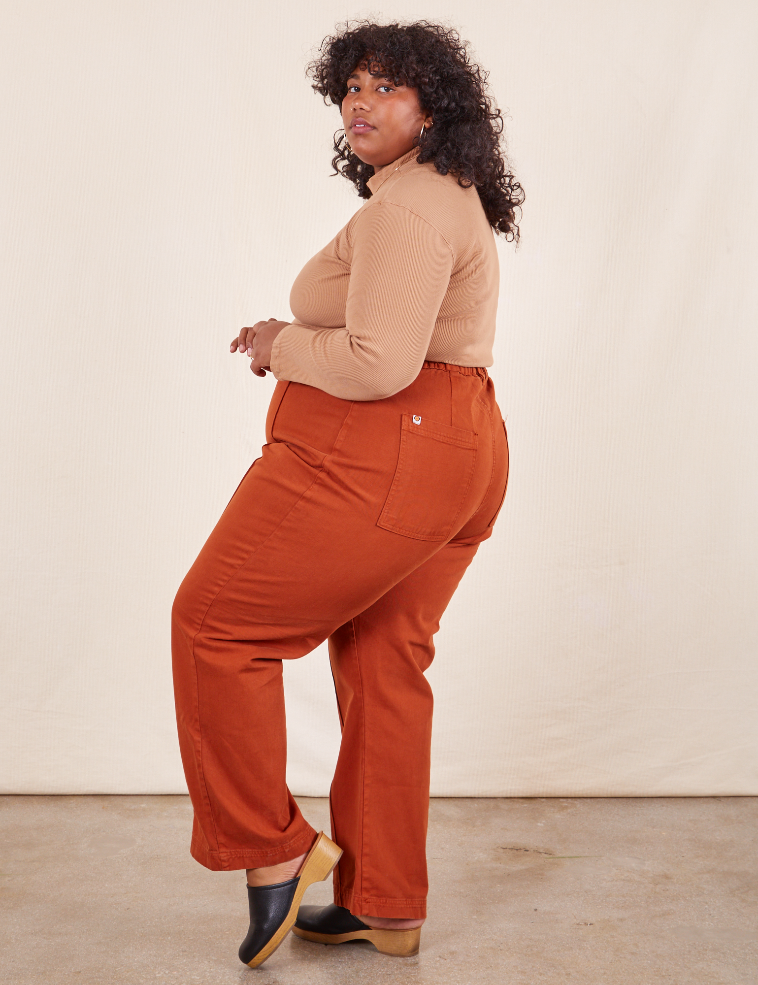 Side view of Western Pants in Burnt Terracotta and tan Essential Turtleneck on Morgan