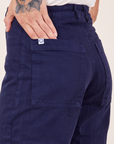 Western Pants in Navy back pocket close up. Jesse has their hand tucked into the pocket.
