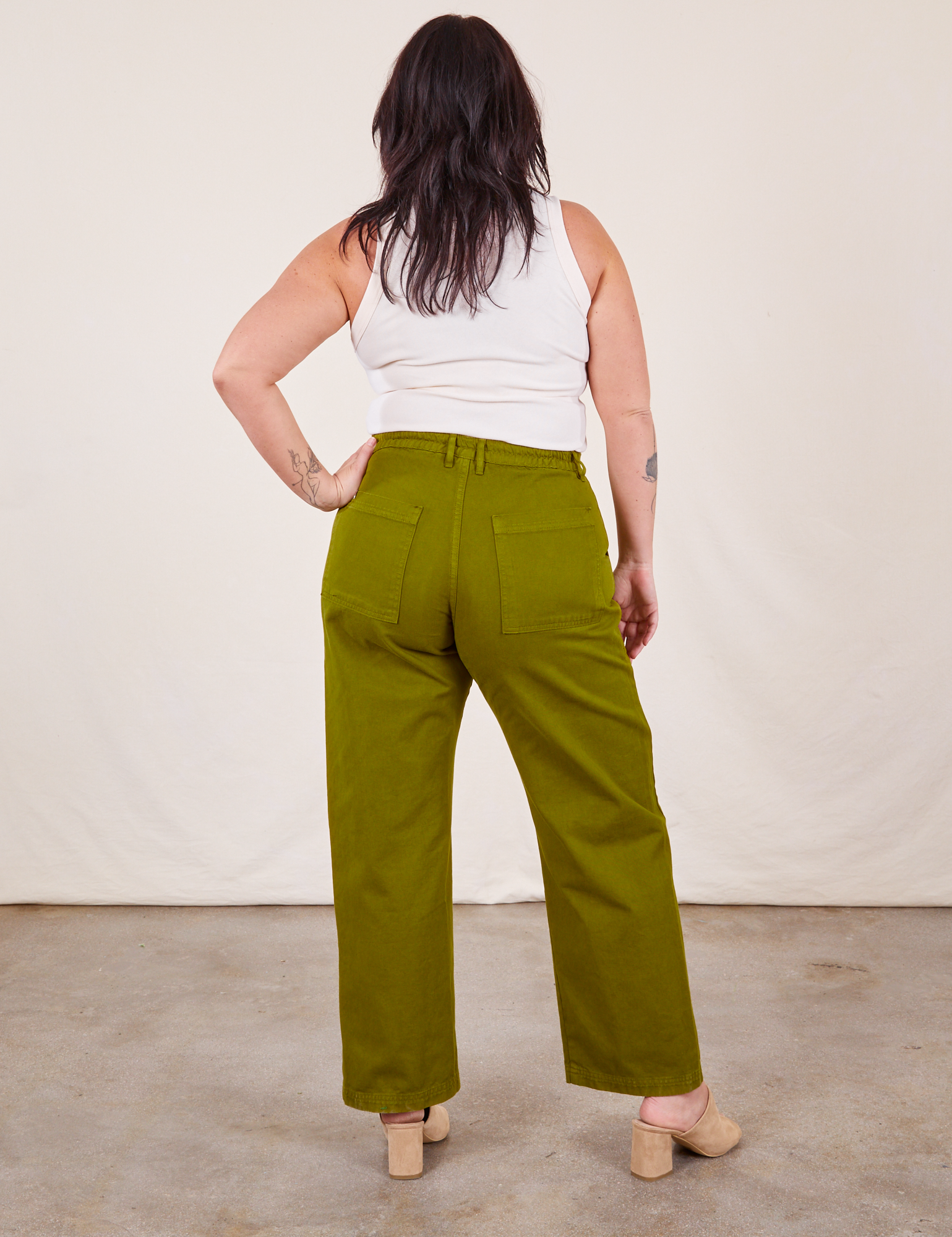 Back view of Work Pants in Olive Green and vintage off-white Tank Top on Faye