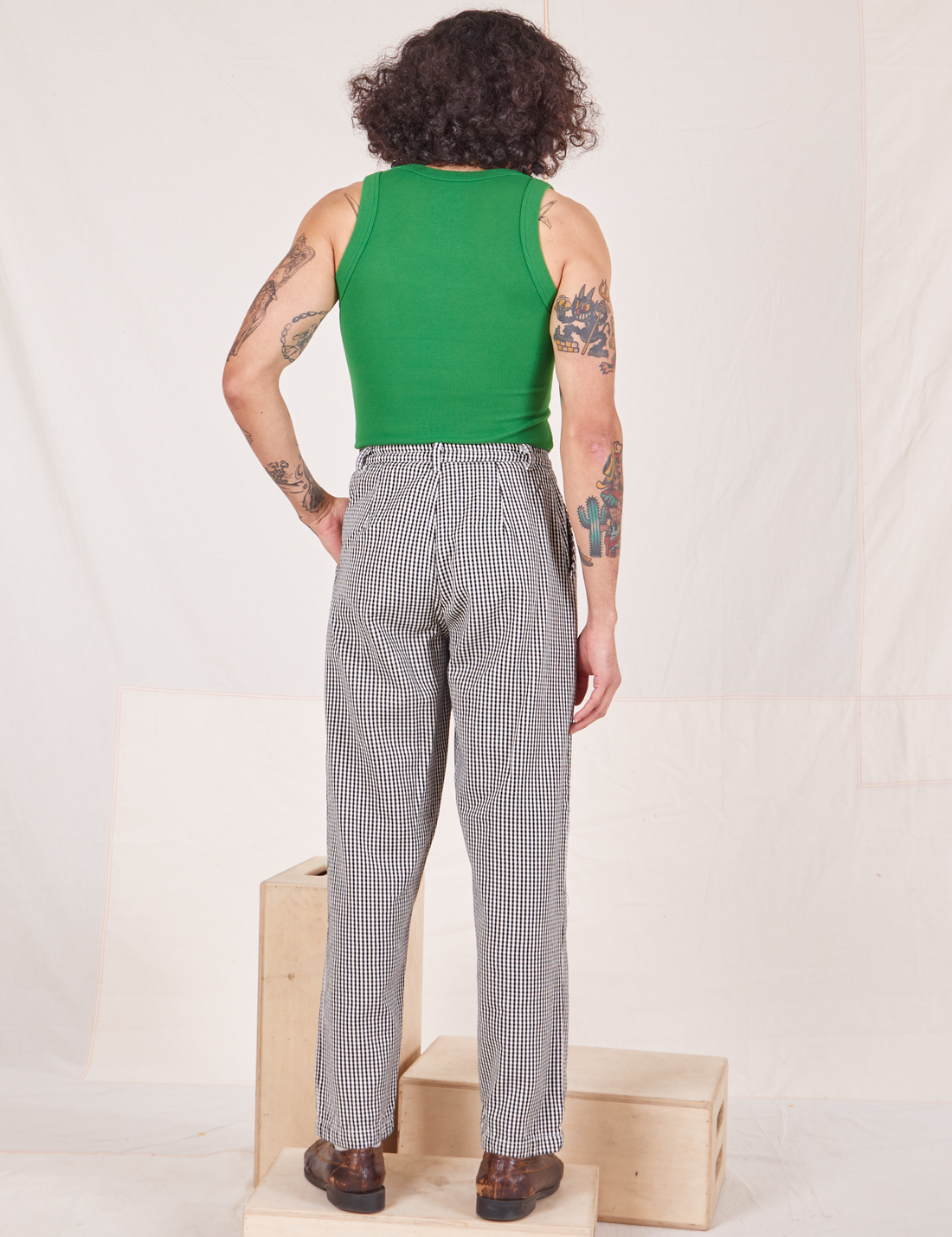 Back view of Checker Trousers in Black & White and forest green Tank Top worn by Jesse