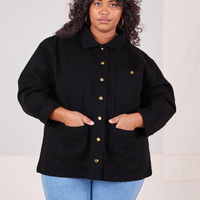 Morgan is wearing a buttoned up Denim Work Jacket in Basic Black and has both hands in the pockets.