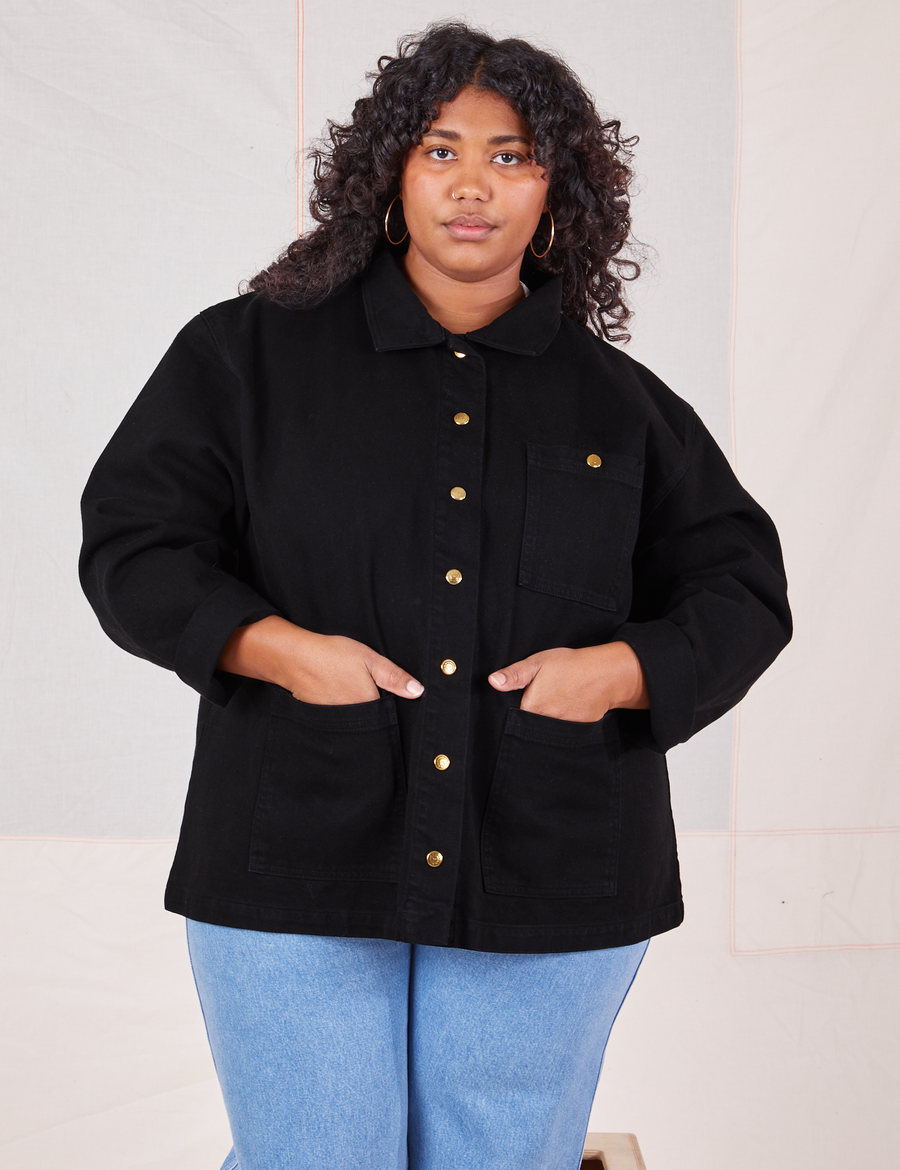 Morgan is wearing a buttoned up Denim Work Jacket in Basic Black and has both hands in the pockets.