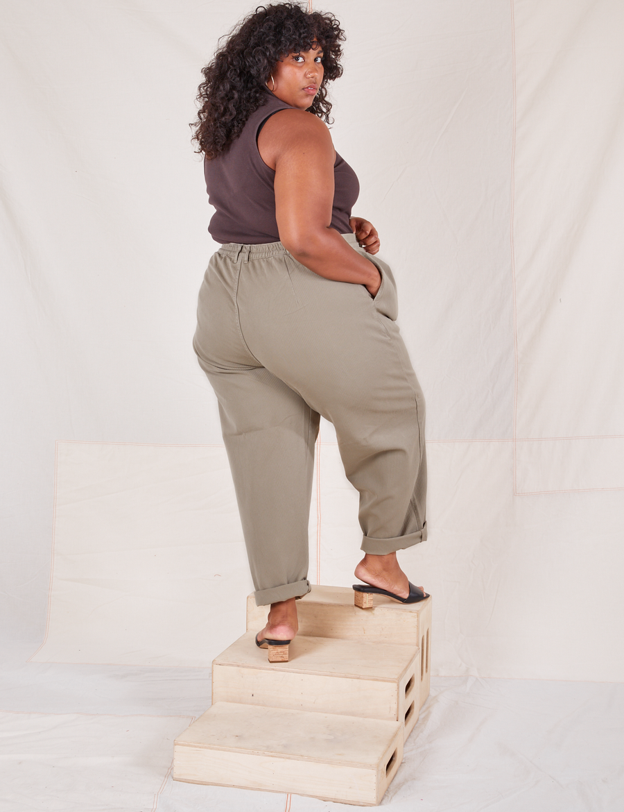Angled back view of Heritage Trousers in Khaki Grey and espresso brown Tank Top worn by Morgan