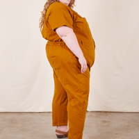 Side view of Short Sleeve Jumpsuit in Spicy Mustard worn by Catie