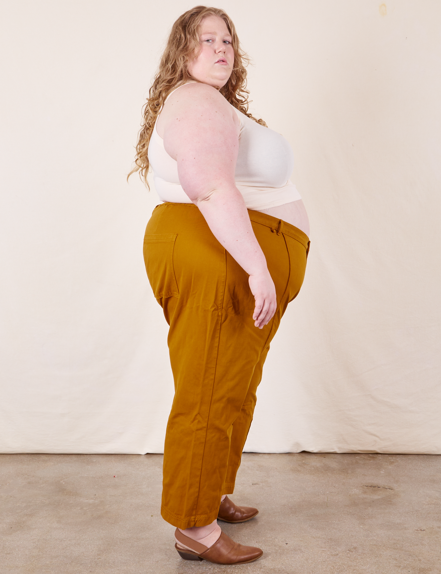 Side view of Western Pants in Spicy Mustard and vintage off-white Tank Top on Catie