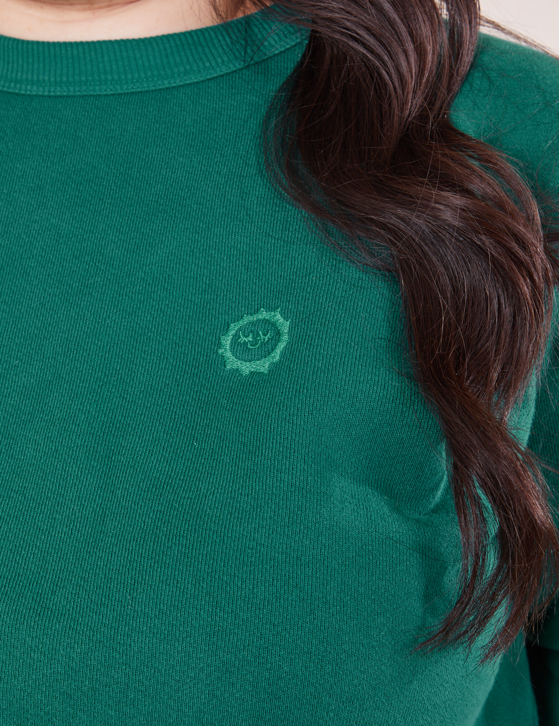 Heavyweight Crew in Hunter Green front close up on Ashley. Embroidered sun baby logo.